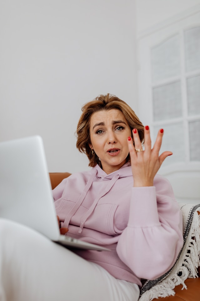A blogger looking frustrated at her laptop while trying to manage Pinterest by hand
